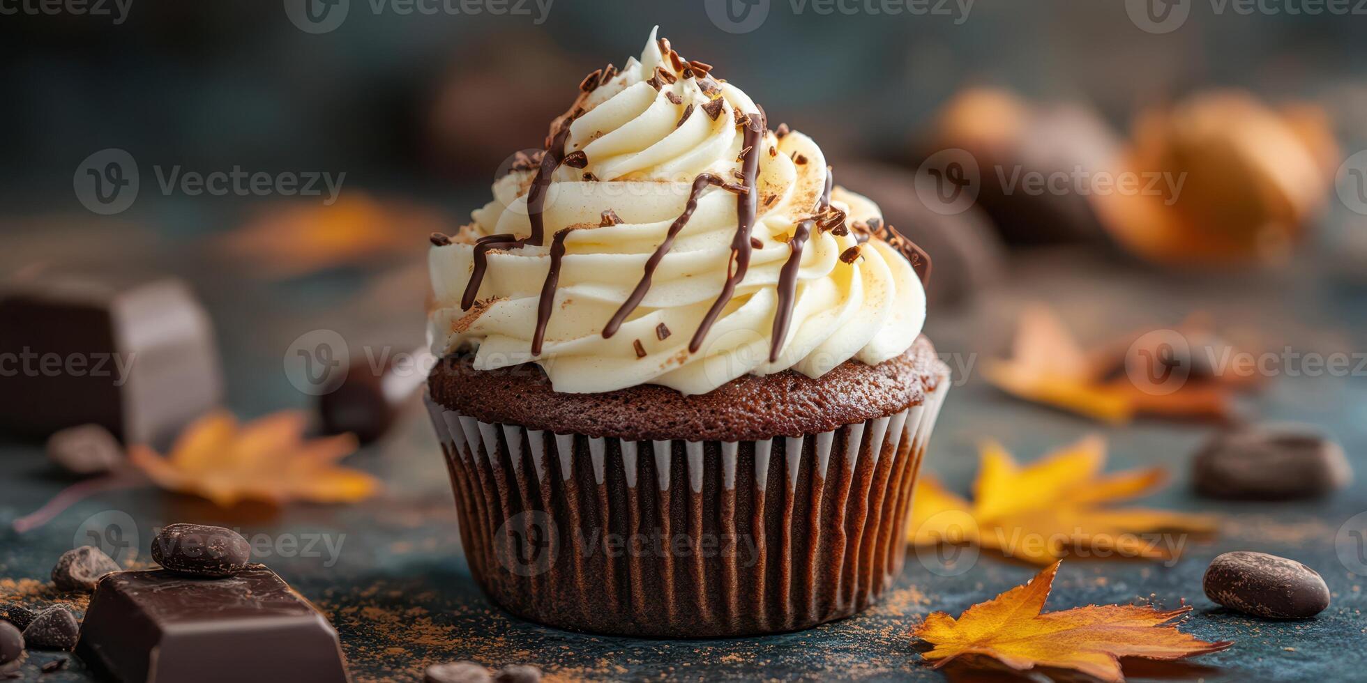Delicious chocolate cupcake topped with creamy frosting and decorated with chocolate drizzle and autumn leaves photo