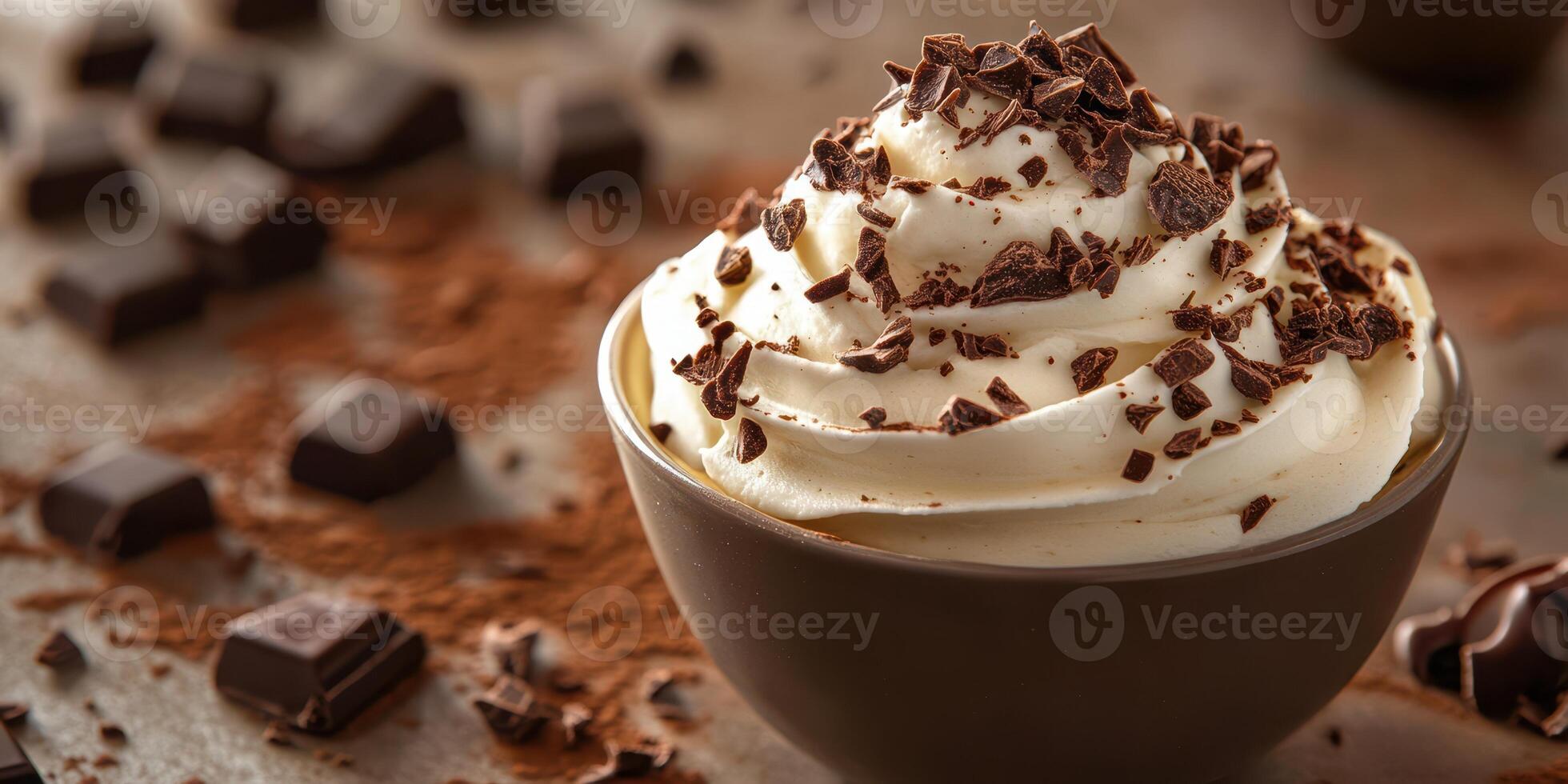 Whipped cream dessert topped with chocolate shavings served in a brown bowl near chocolate pieces photo
