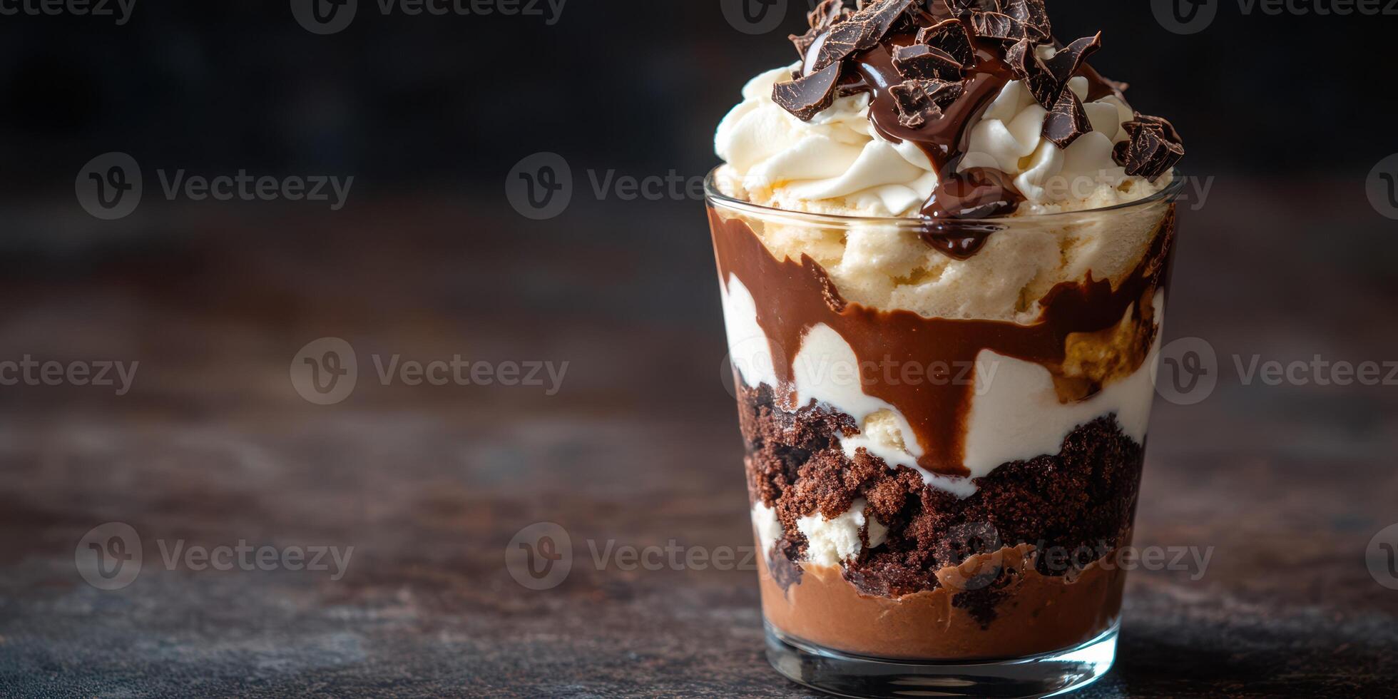 Delicious chocolate dessert with layers of cake, whipped cream, and chocolate shavings in a glass cup photo