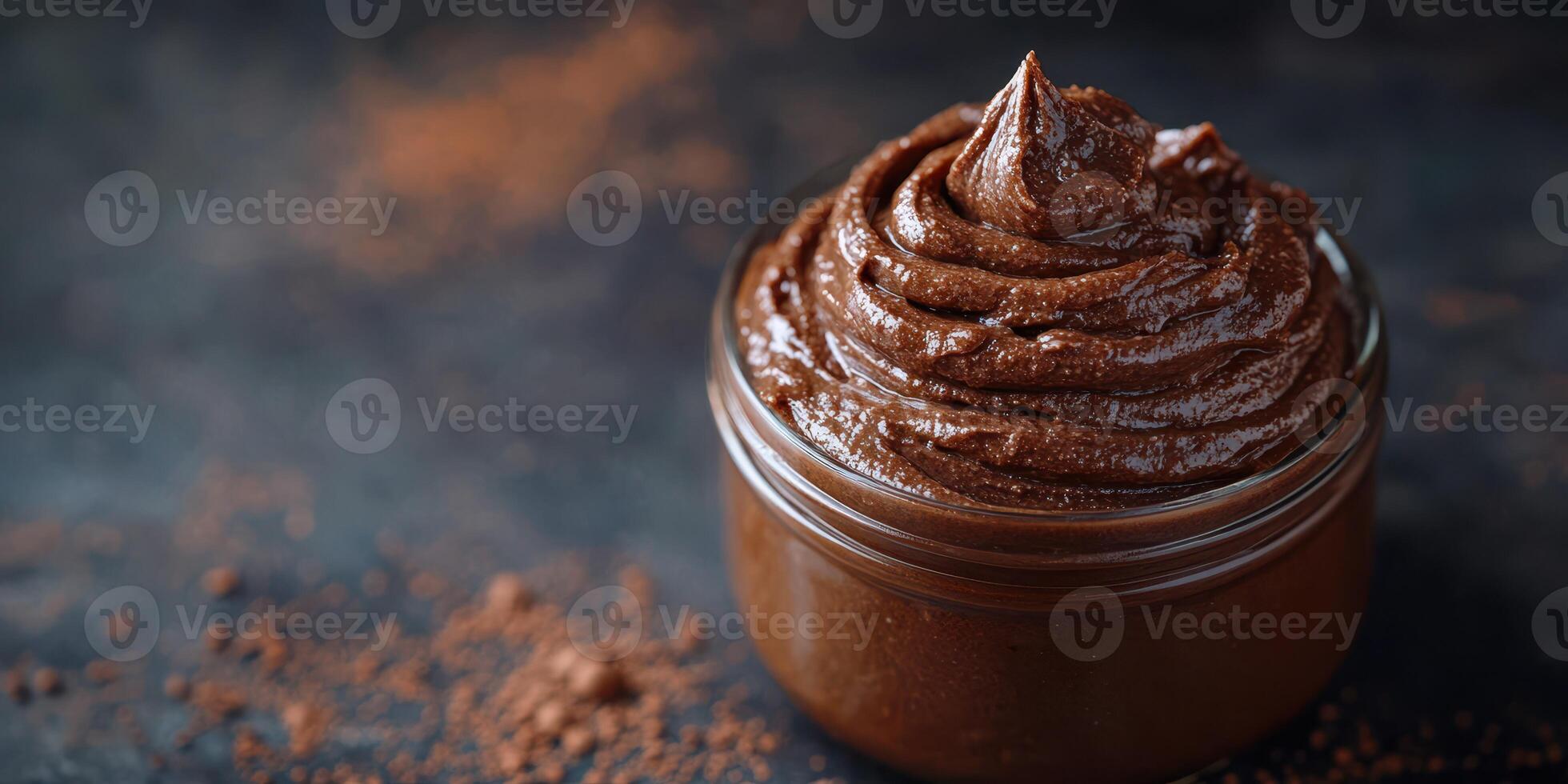 Chocolate spread in a glass jar with rich, creamy texture and cocoa powder on a dark surface photo