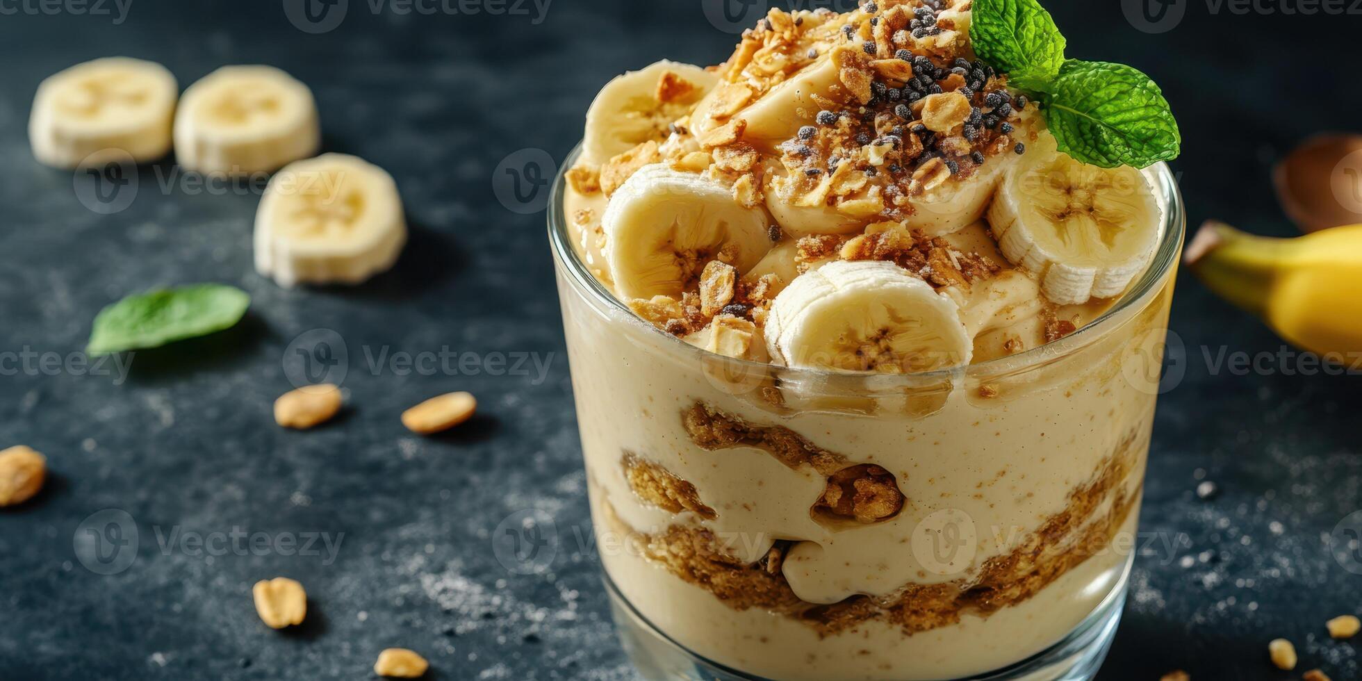 Delicious banana parfait with granola and mint served in a clear glass on a dark surface photo