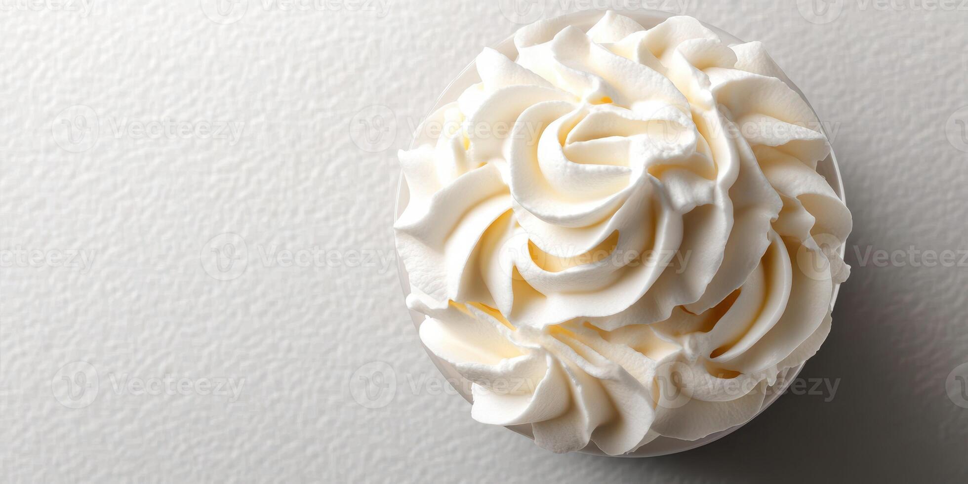 Whipped cream swirl in a clear cup on a textured white surface captured in a cozy kitchen setting photo