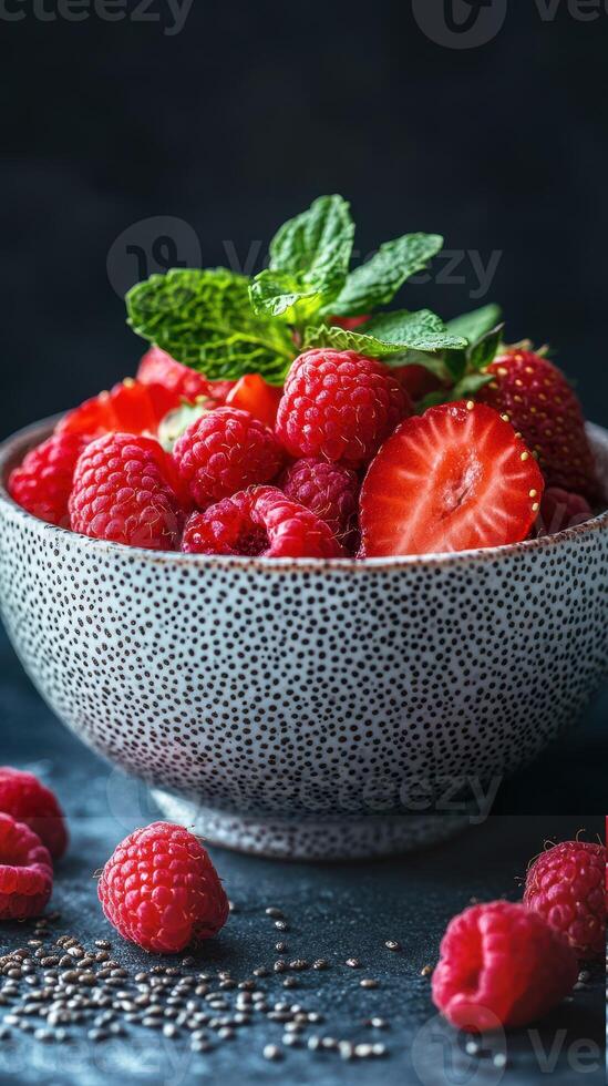 Fresh raspberry and strawberry bowl garnished with mint leaves on a textured dark background in a cozy kitchen setting photo
