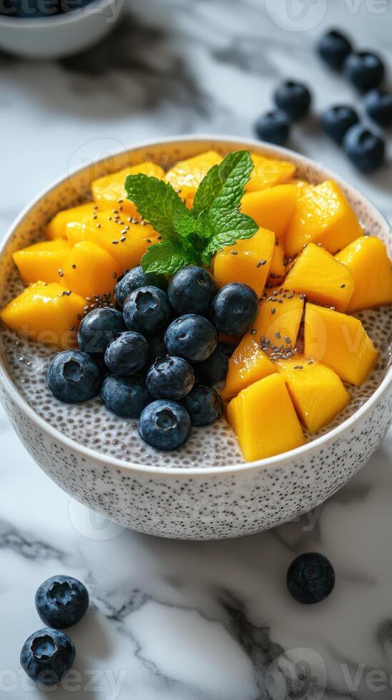 Healthy chia seed pudding topped with fresh mango and blueberries on a marble countertop photo