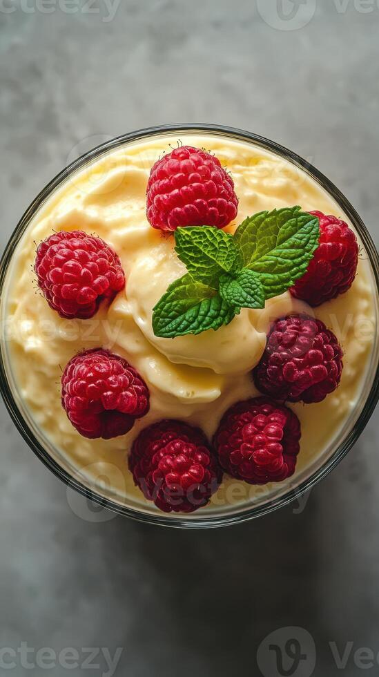 Rich raspberry dessert features creamy texture and fresh berries on top in a glass bowl photo