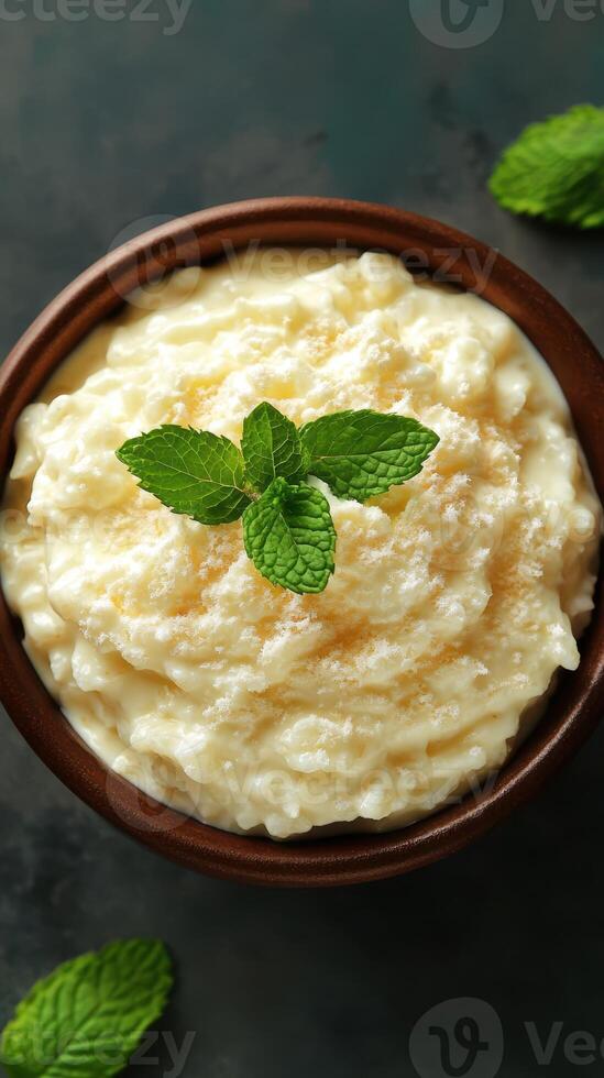 Creamy dessert topped with mint leaves served in a rustic bowl on a dark background photo