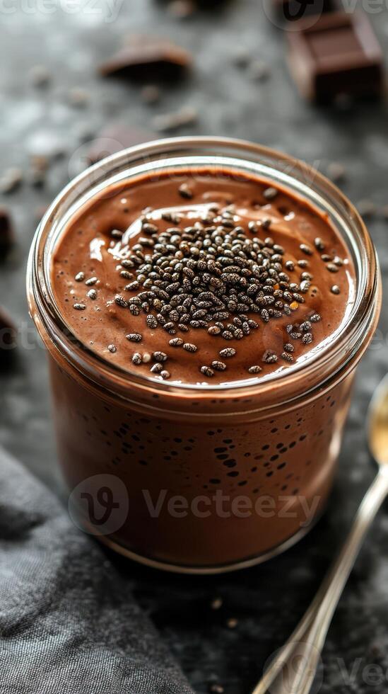 Creamy chocolate pudding topped with chia seeds in a glass jar on a rustic table setting photo