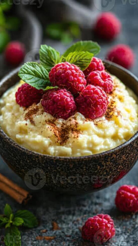 Creamy rice pudding topped with fresh raspberries and mint leaves served on a rustic table photo