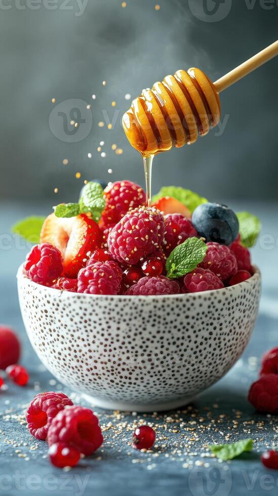 Freshly picked berries drizzled with golden honey in a textured bowl on a soft blue background photo