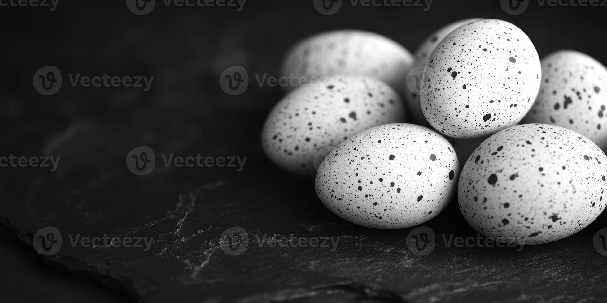 Beautifully speckled eggs arranged on a dark surface in a monochrome setting photo