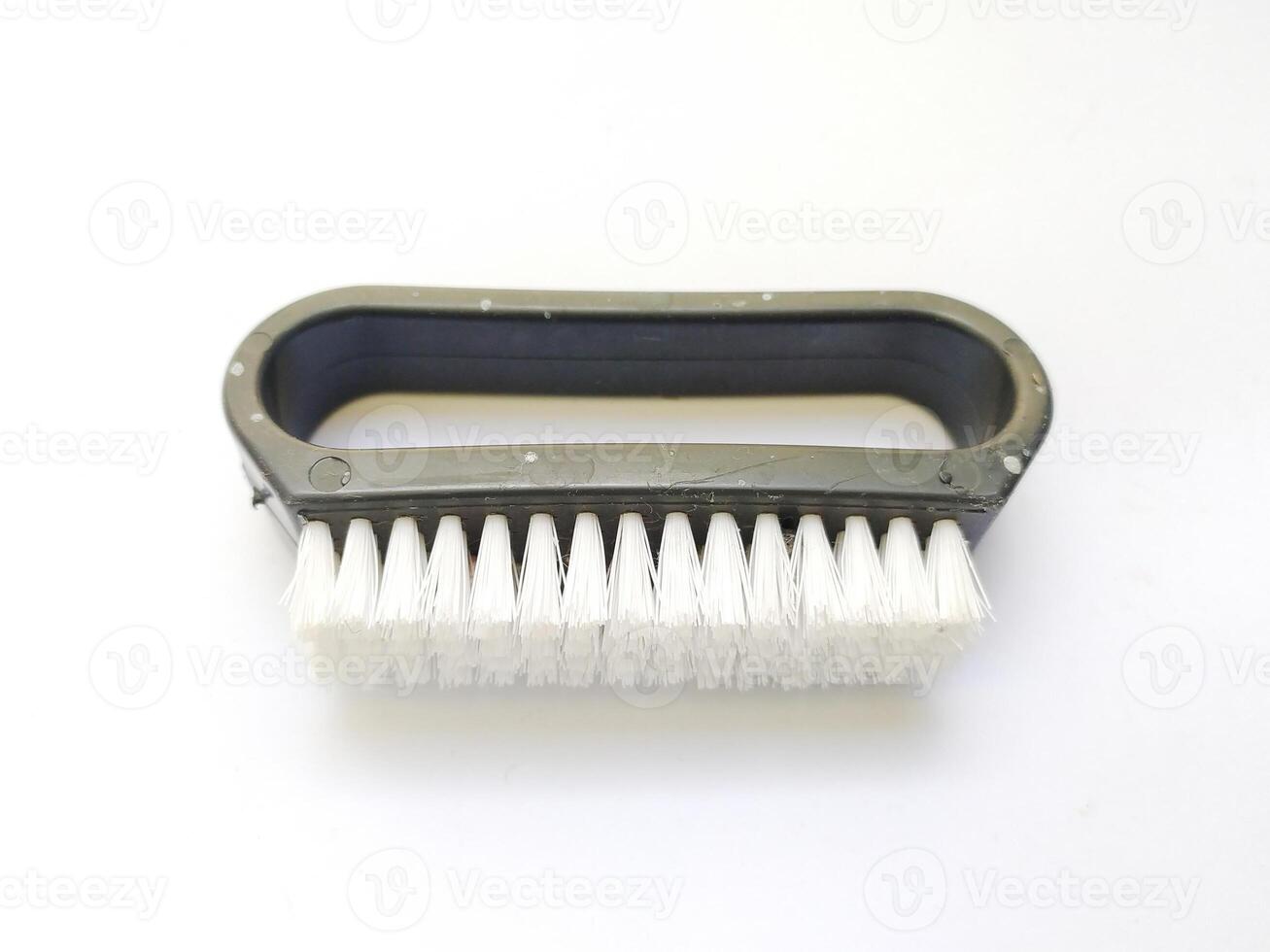 Closeup of a small, handheld brush with white bristles and a dark gray plastic handle. Perfect for illustrating cleaning, detail work, or the concept of meticulousness. photo