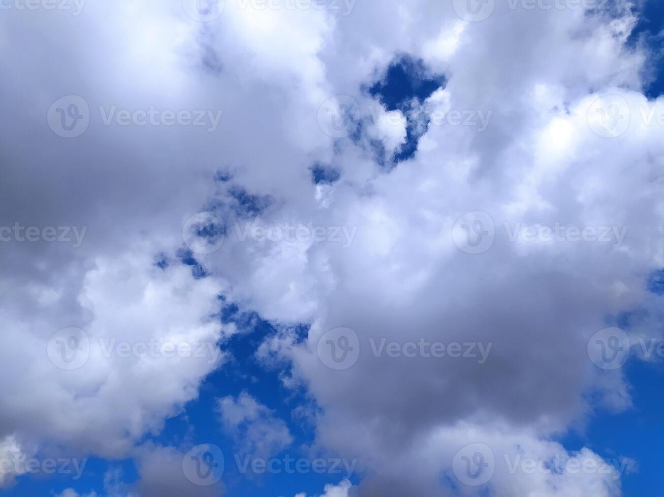 Dramatic cloudscape featuring fluffy white and dark gray cumulus clouds against a vibrant blue sky. Perfect for backgrounds, websites, or any project photo