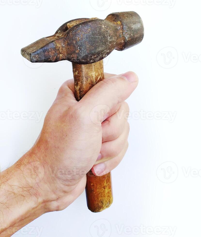 A weathered claw hammer, held firmly in a mans hand, symbolizes strength, craftsmanship, and hard work. The rustic texture and worn wood handle add character and authenticity. photo