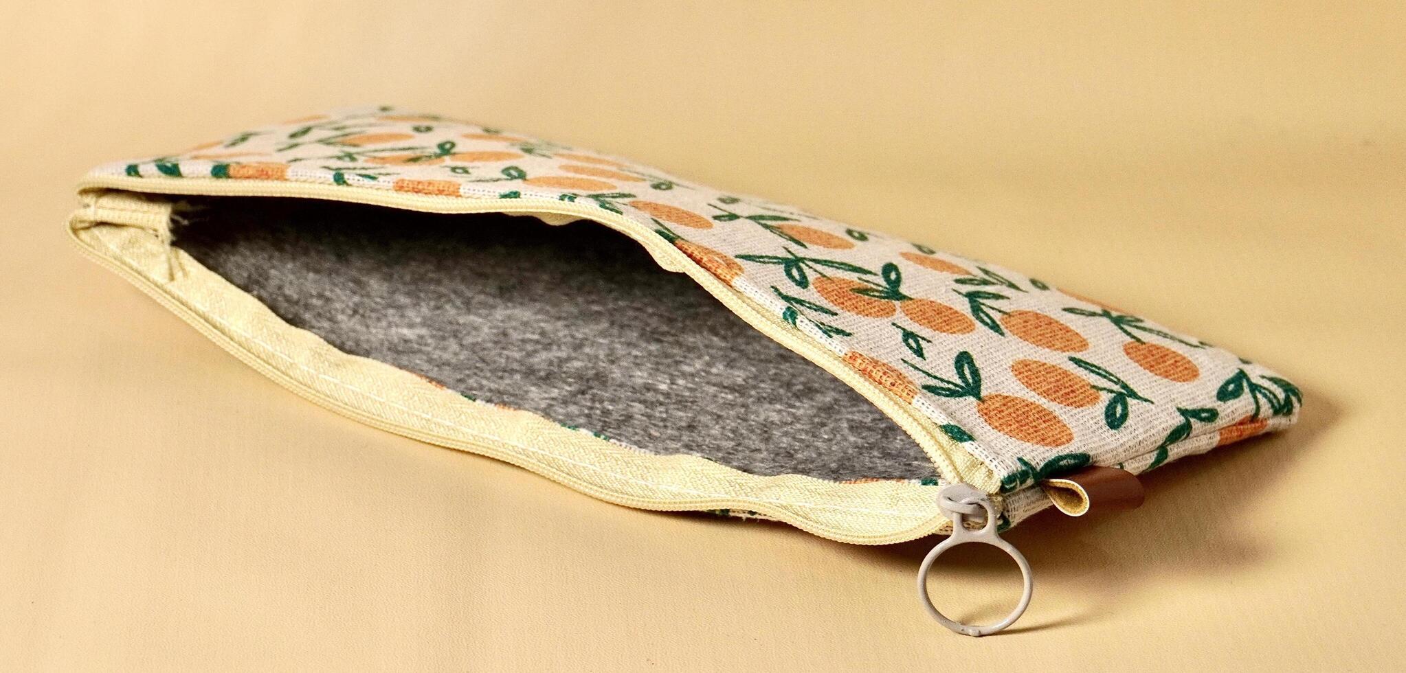 Empty opened pencil case with orange fruit fabric design isolated on horizontal brown cream background. photo