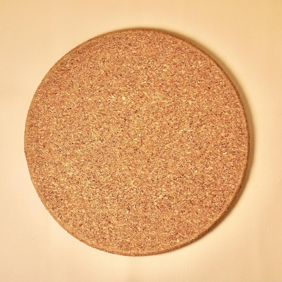 Brown round cork place mat coaster kitchenware isolated on brown cream background from top angle view. photo