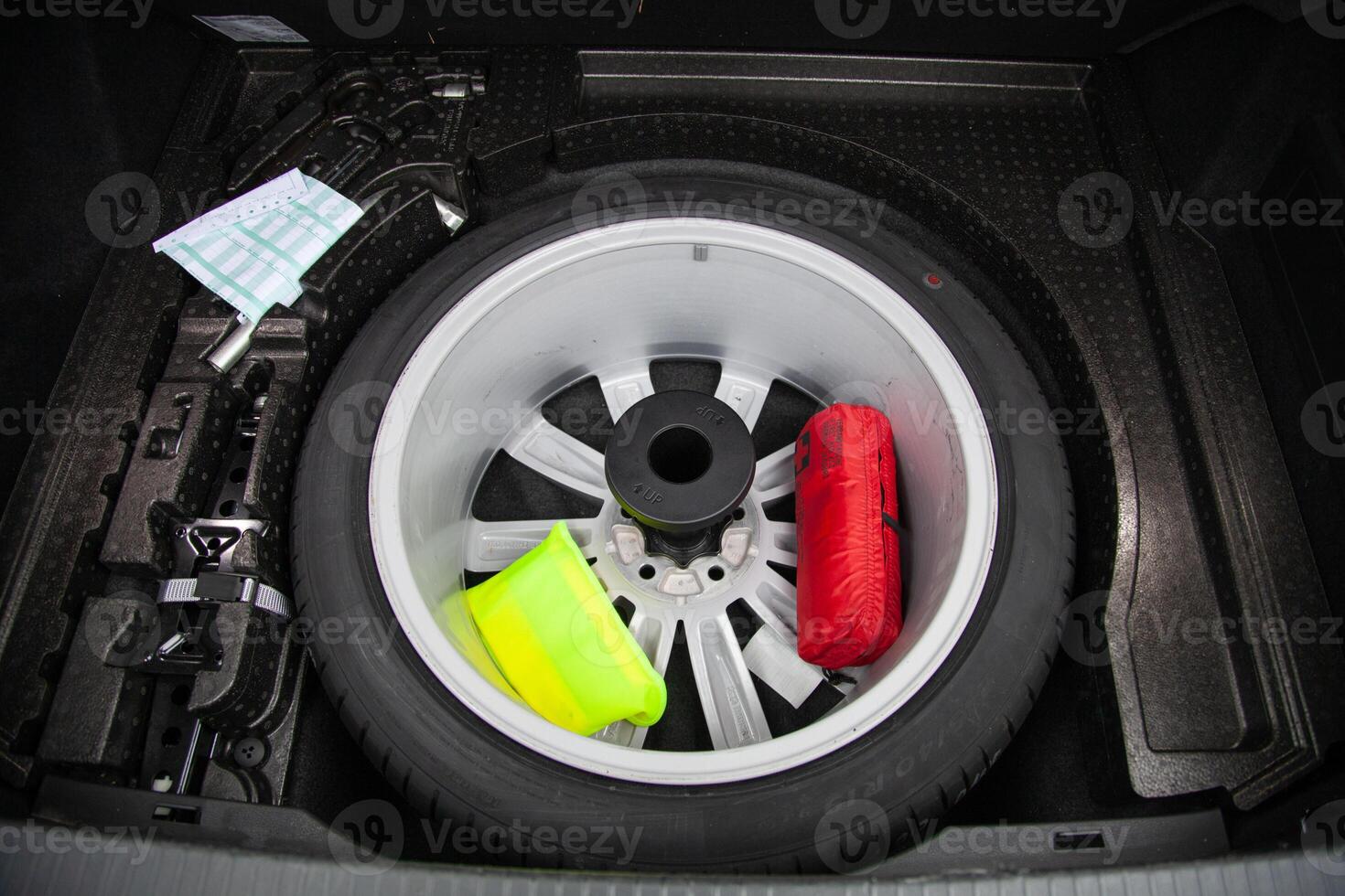 Spare tire, reflective vest, first aid kit and emergency sign in the car trunk under the floor photo