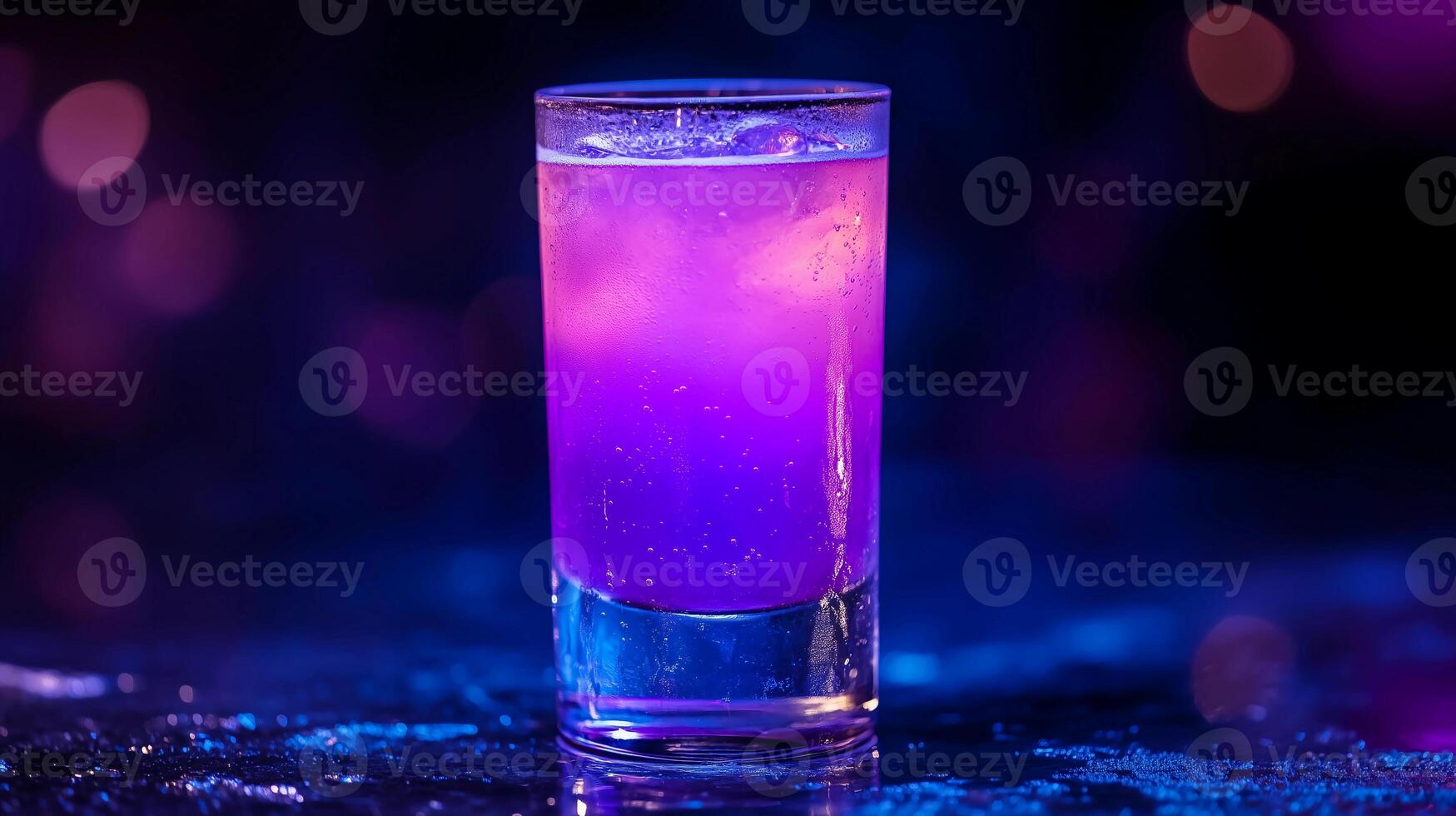 A purple drink in a glass is sitting on a table. The drink is purple and has a clear liquid in it photo