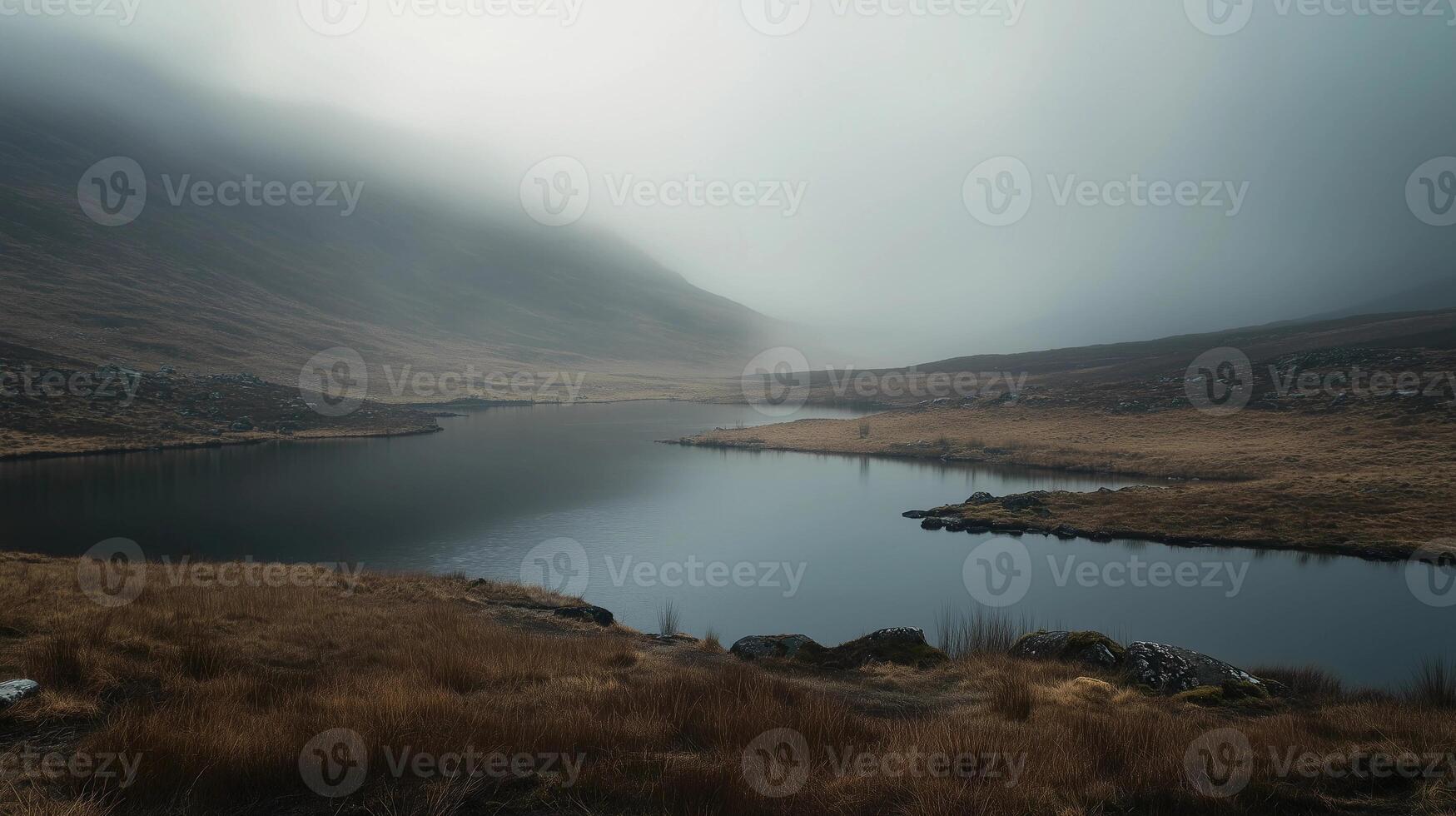 A lake is surrounded by a field of grass. The sky is overcast and the water is calm photo