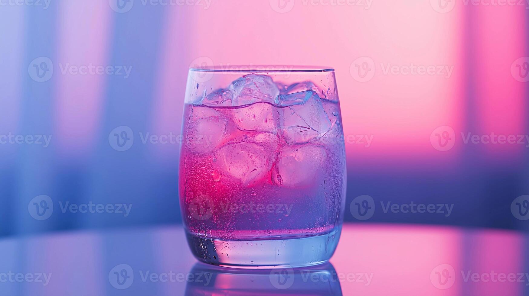 A glass of pink drink with ice cubes in it is sitting on a table. The drink is a mix of different flavors, giving it a unique and refreshing taste. The ice cubes are clear photo