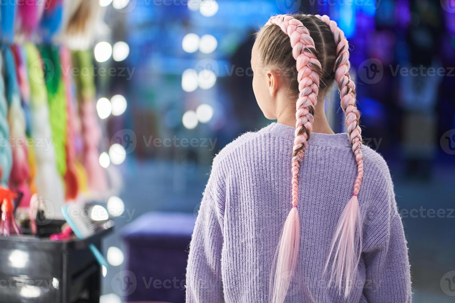 A child with pigtails made of pink kanekalon. Showing off her braided hair. There is a place to copy photo