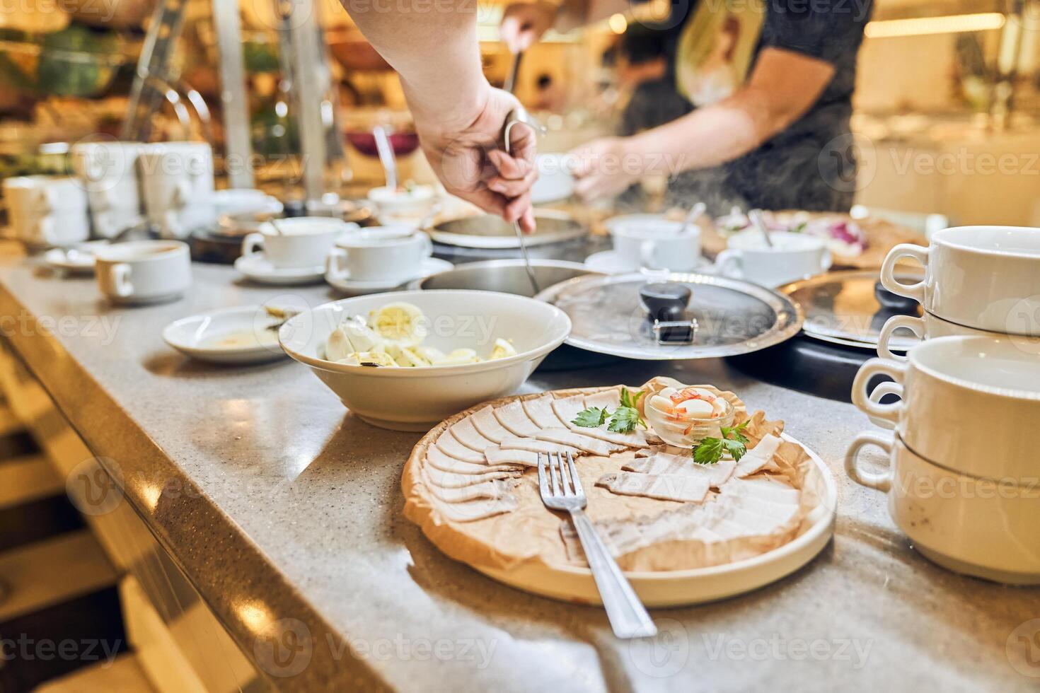 A person selects and serves breakfast dishes in the hotel restaurant. Buffet for a hearty lunch with space for copying photo