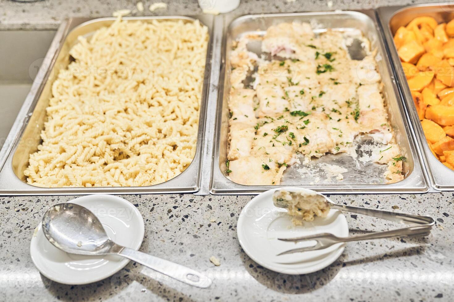 Close-up of hot food items pasta and baked fish. Free food in the charity canteen, with space for copying photo