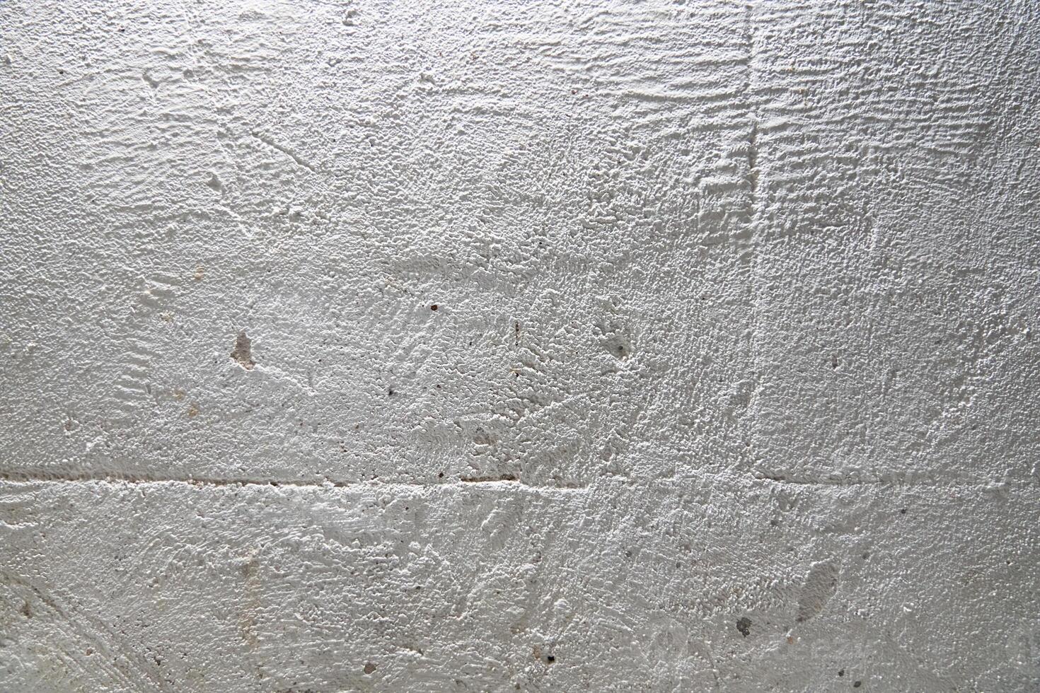 The grainy texture of a stone white wall. Uneven surface with space for copying photo