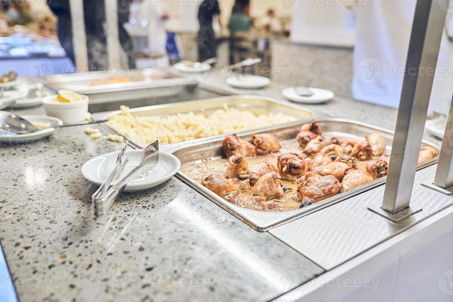 An event in a restaurant with a healthy buffet. Delicious dishes for a late dinner on plates. The chicken tongs are next to the metal containers. photo