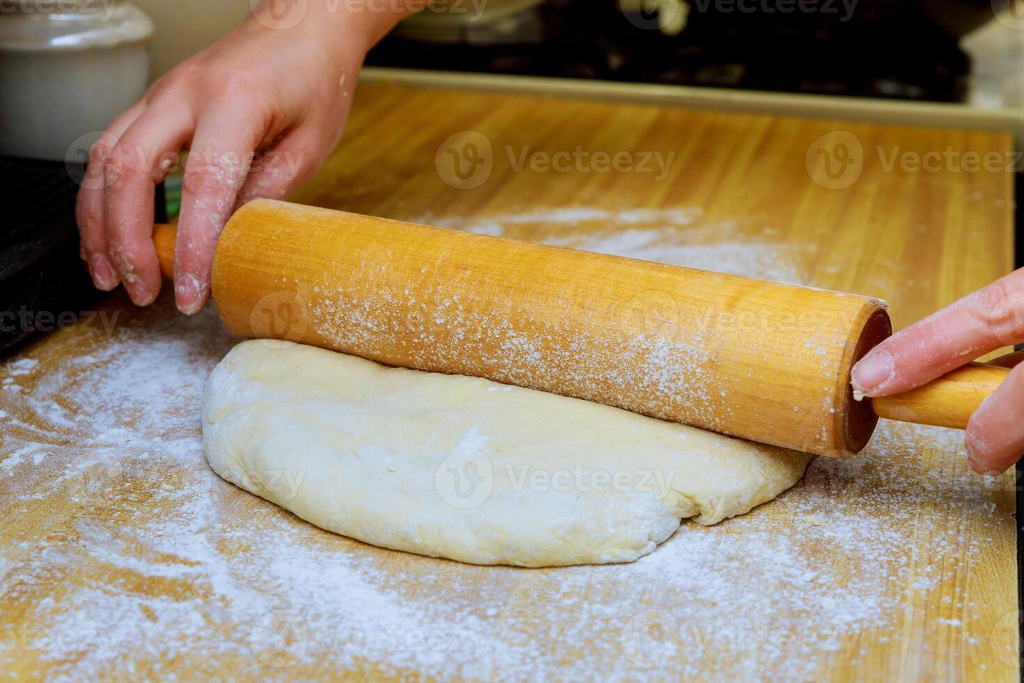 closeup of hands using rolling pin on dough on the table photo
