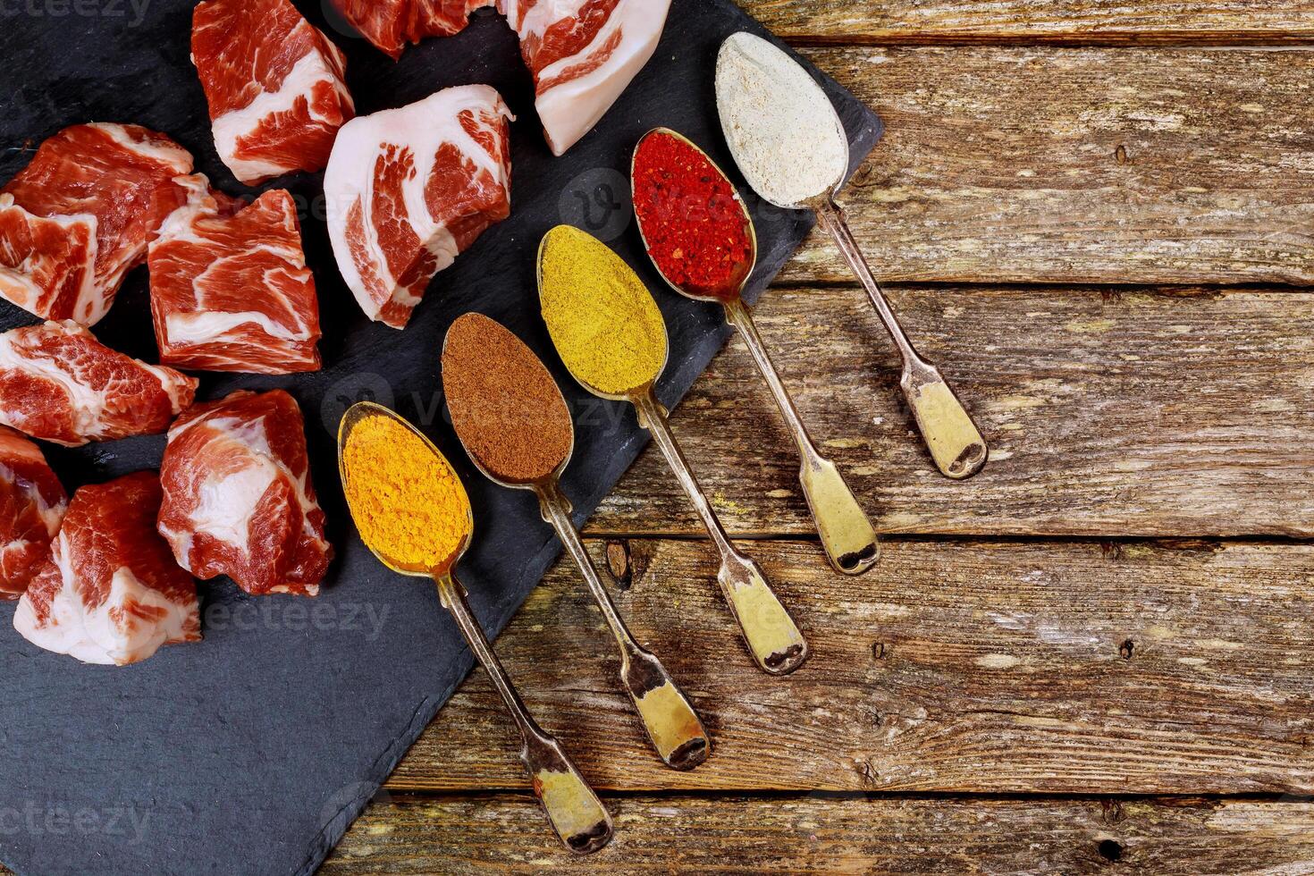 Perfect Raw Pork Neck with spoons with different spices Wooden Cutting Board. Top View photo