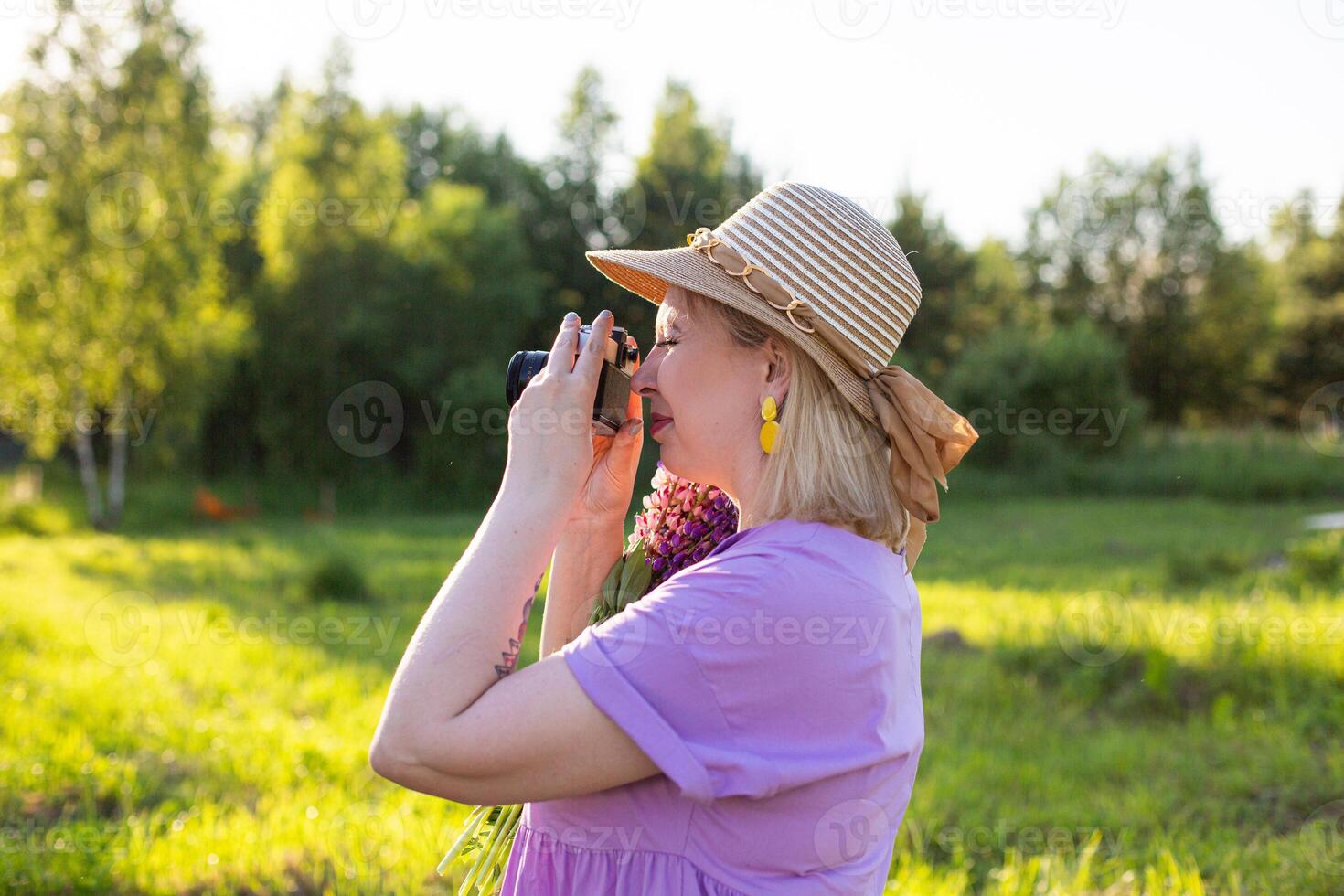 A woman in a hat taking a photo of flowers