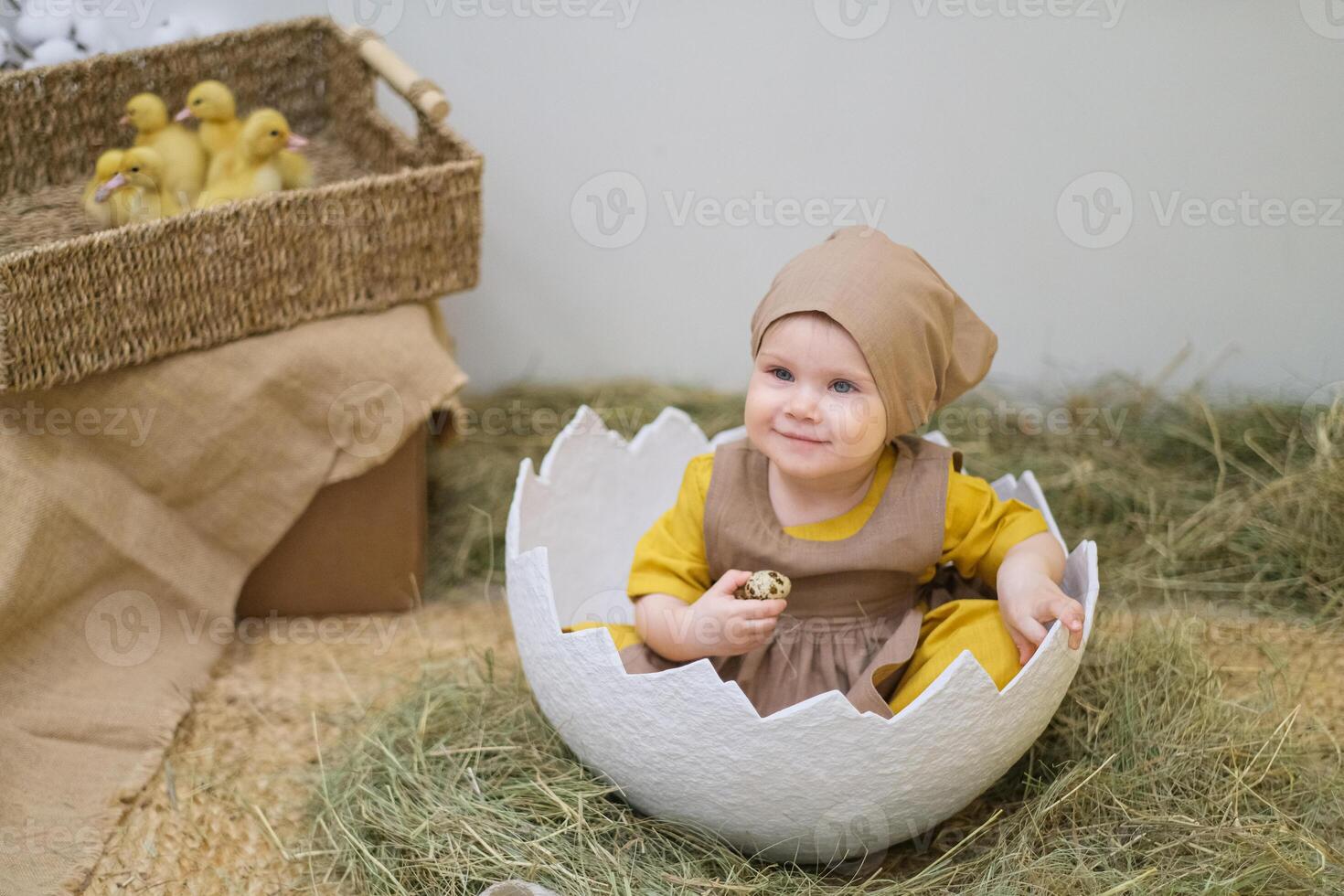 A baby in a brown outfit sitting in an egg photo