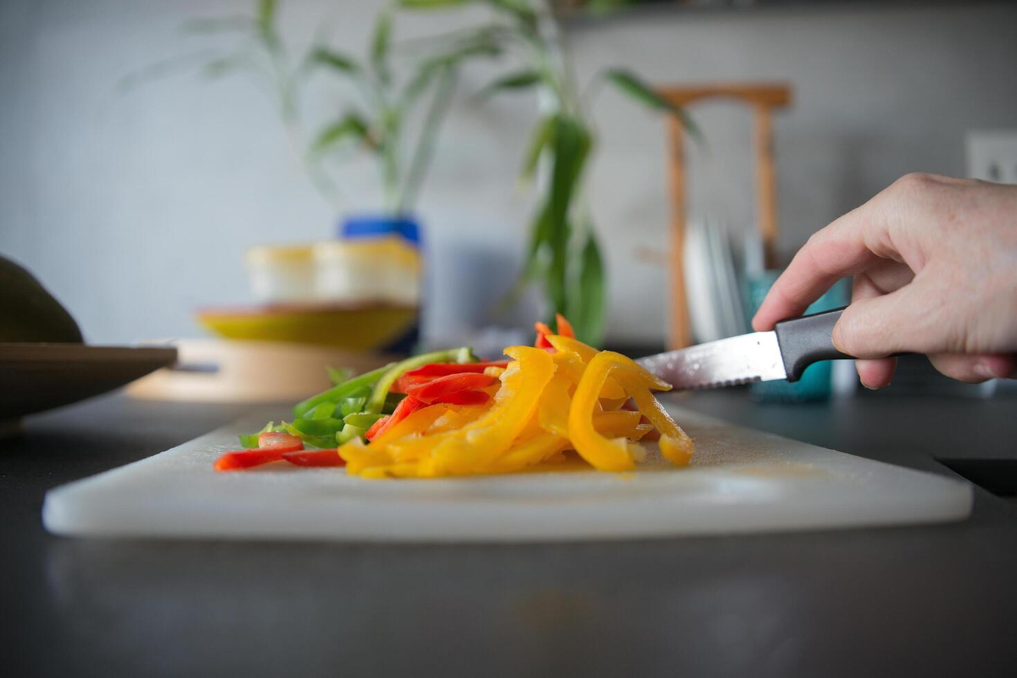 Unrecognizable woman hand with a knife cutting vegetables in a kitchen counter photo
