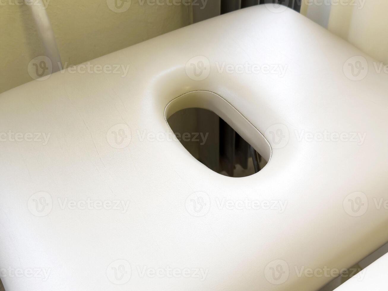 Clean foam massage table headrest with face cutout in relaxation room photo