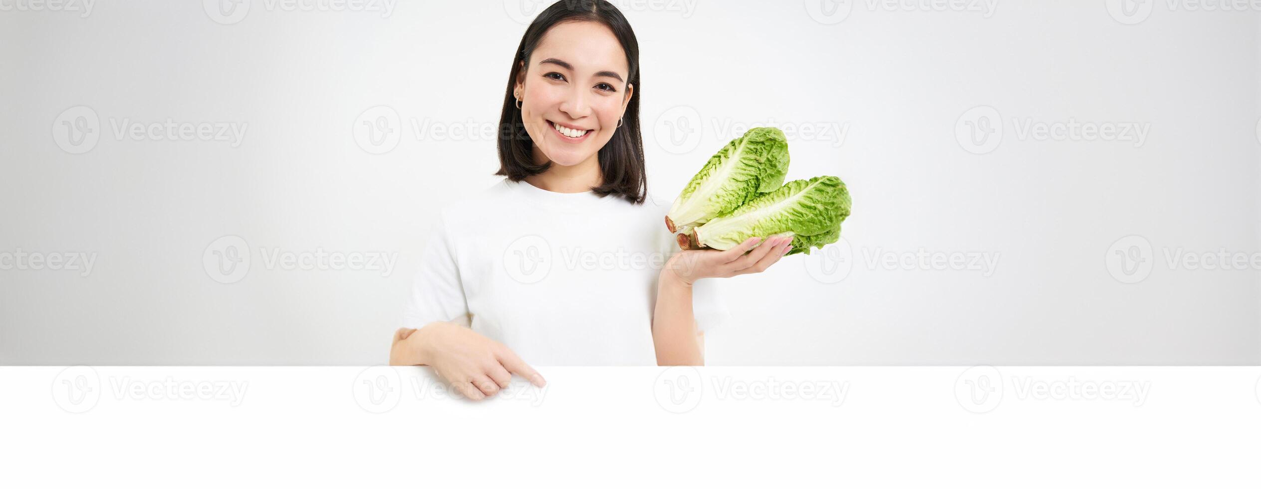 Nutrition and healthy food. Smiling japanese woman shows cabbage, fresh lettuce, isolated on white background photo