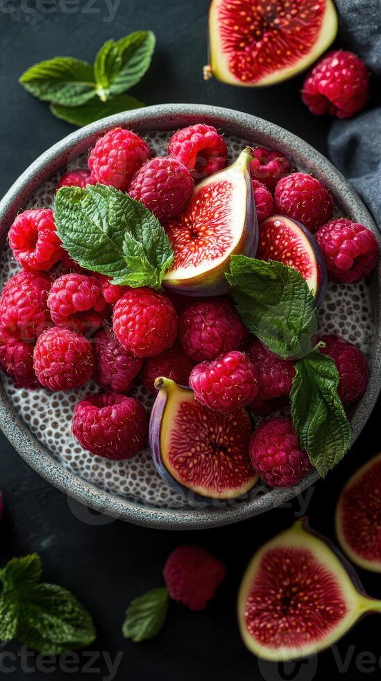 Bright and vibrant assortment of fresh raspberries and figs arranged in a bowl with mint leaves on a dark surface photo