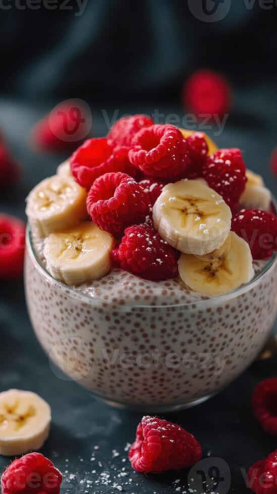 Delicious chia pudding topped with fresh raspberries and sliced bananas on a dark background photo