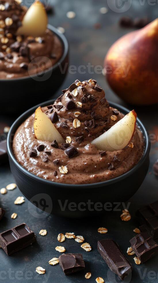 Chocolate mousse topped with pear slices and chocolate pieces served in elegant black bowls photo
