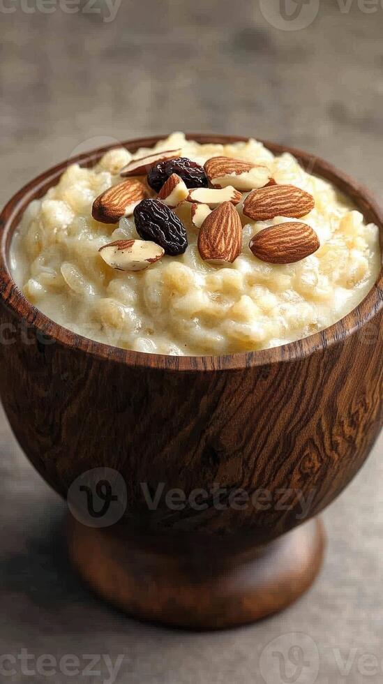 Creamy rice pudding topped with almonds and raisins served in a wooden bowl photo