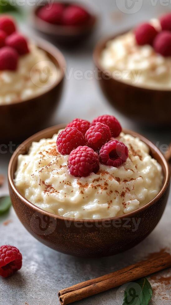 Creamy rice pudding topped with fresh raspberries and cinnamon served in wooden bowls on a gray surface photo