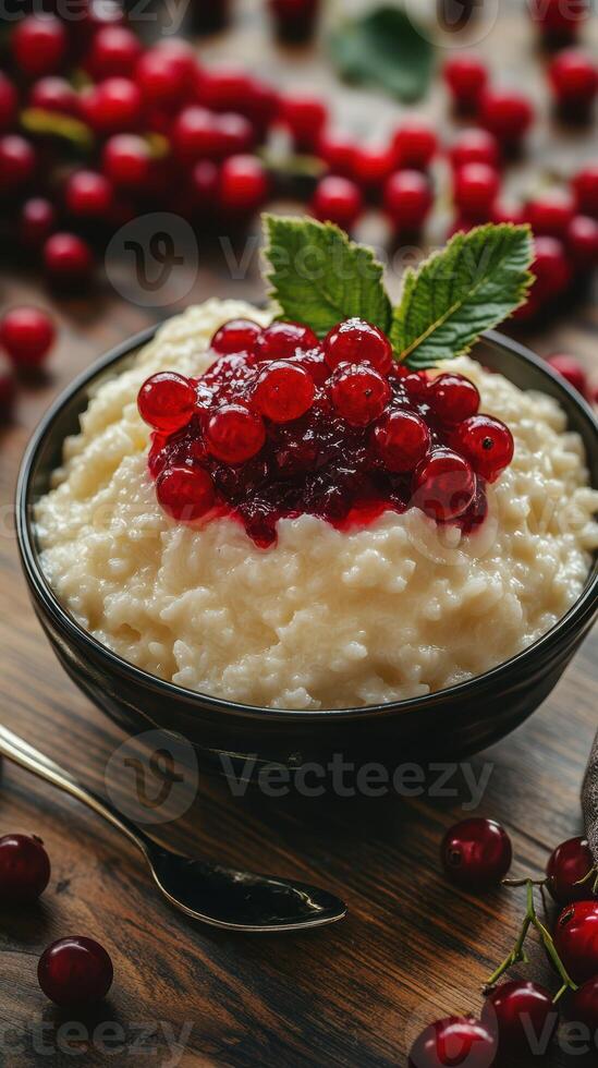 Creamy rice pudding topped with fresh red currants and a mint leaf on a rustic wooden table photo