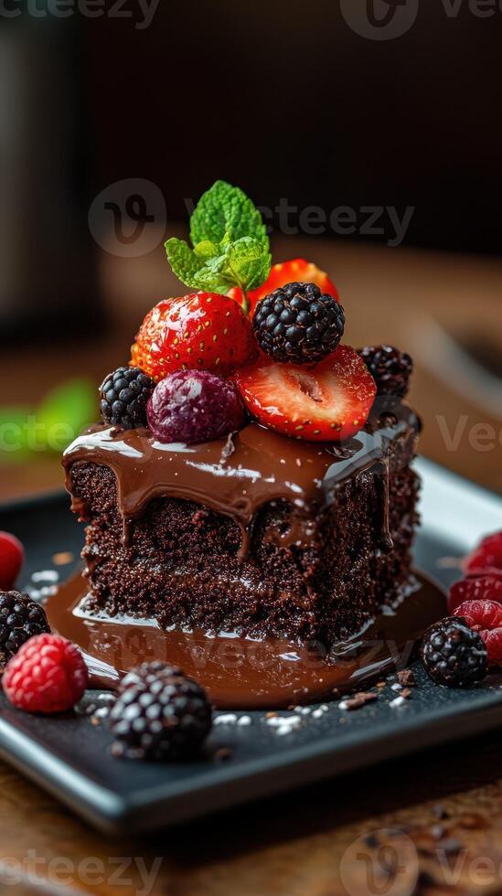 Decadent chocolate cake topped with fresh berries served on a black plate in a cozy setting photo