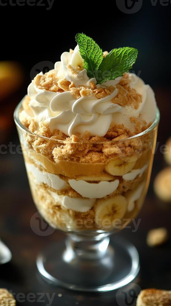Delightful dessert featuring layers of whipped cream, bananas, and crushed cookies in a clear glass cup photo