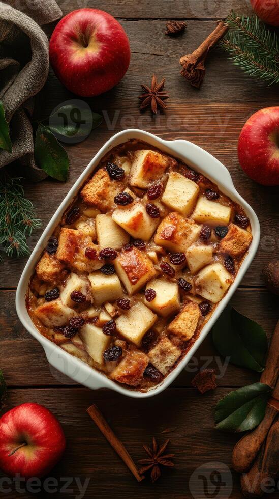 Delicious apple bread pudding with spices and raisins served in a white dish on a wooden table photo