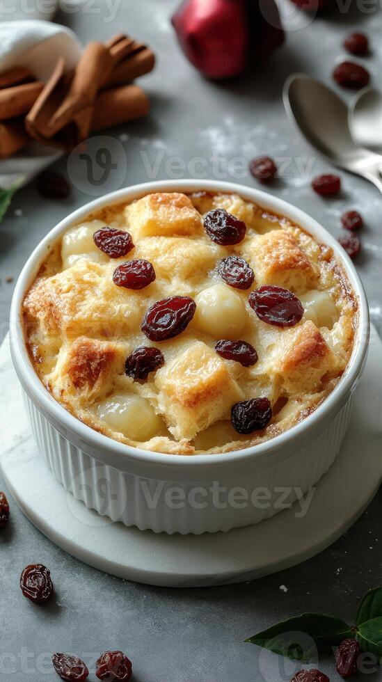 Delicious bread pudding with raisins and spices served in a white dish on a gray background photo