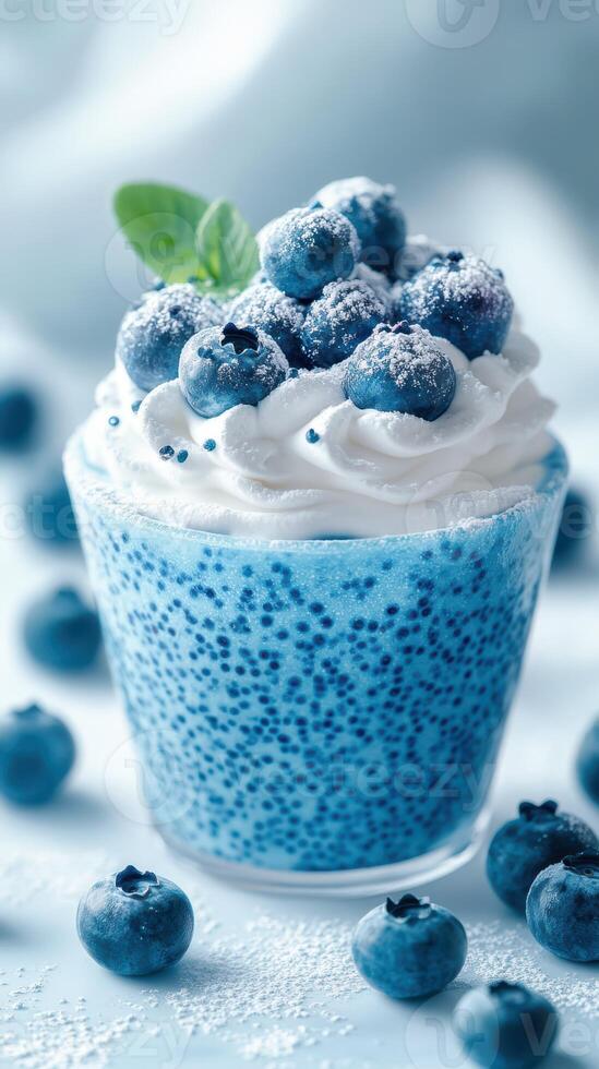 Blueberry dessert with whipped cream and fresh blueberries on top served in a clear glass cup photo