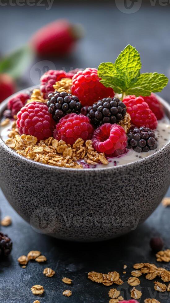 A bowl of yogurt topped with fresh berries and granola on a dark surface in a cozy kitchen setting photo