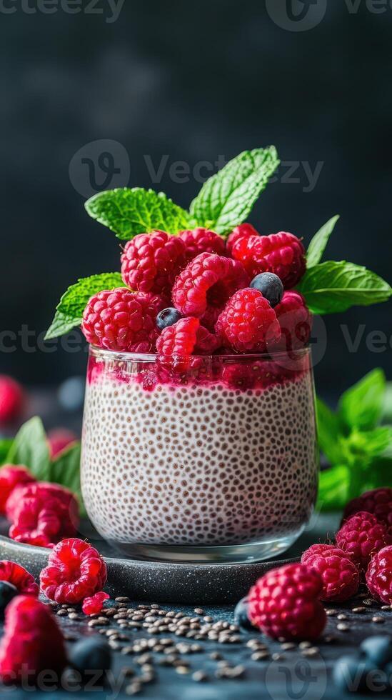 Creamy chia seed pudding topped with fresh raspberries and mint leaves placed on a dark background photo