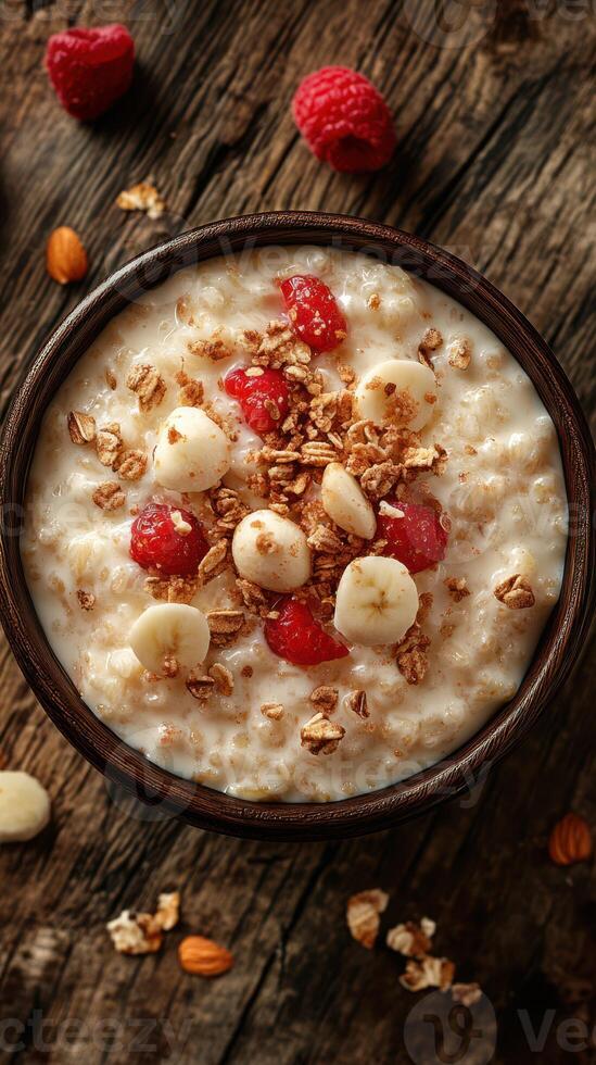 Delicious bowl of oatmeal topped with fresh bananas and raspberries on rustic wooden table photo
