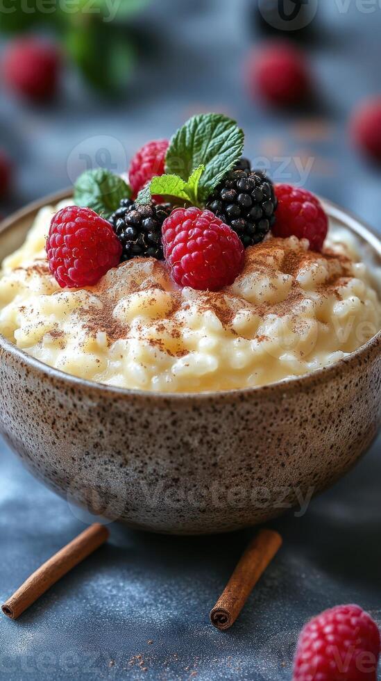 Creamy rice pudding topped with fresh berries and mint leaves in a rustic bowl on a dark surface photo